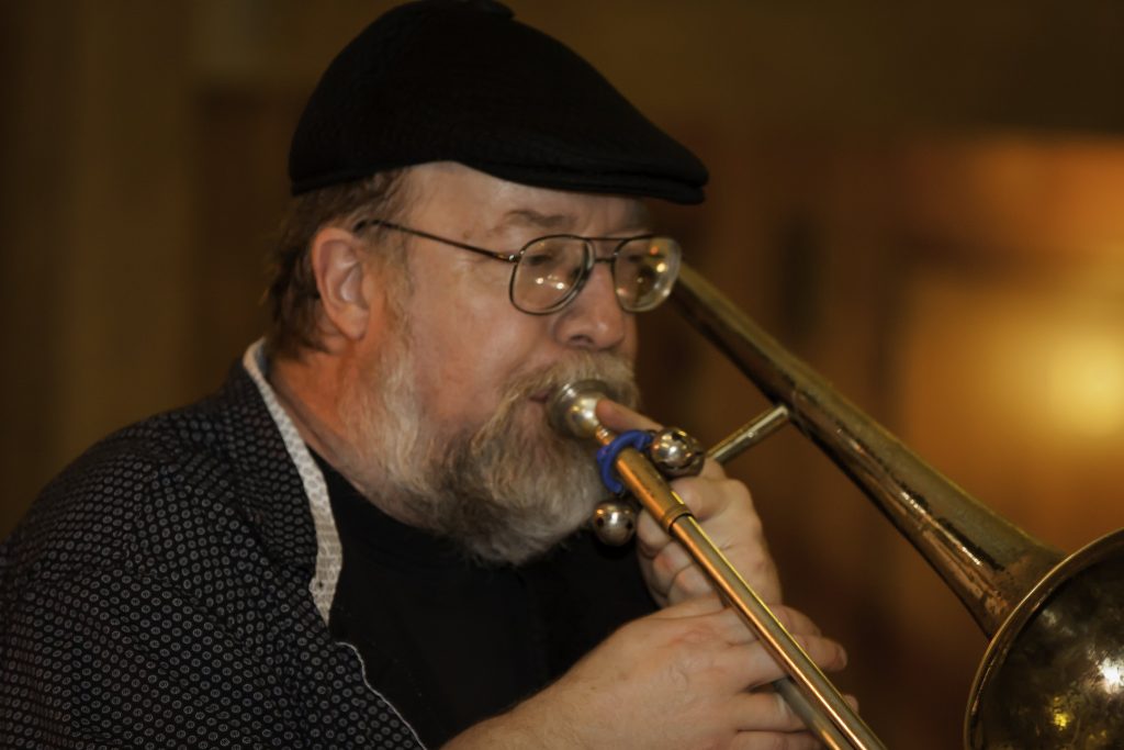 Jim Messbauer playing the trombone, with a blurred background