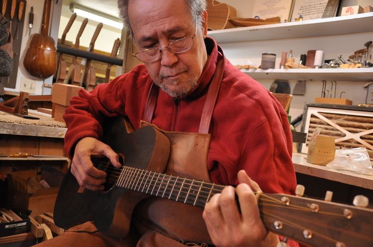 William Cumpiano playing a guitar in his workshop