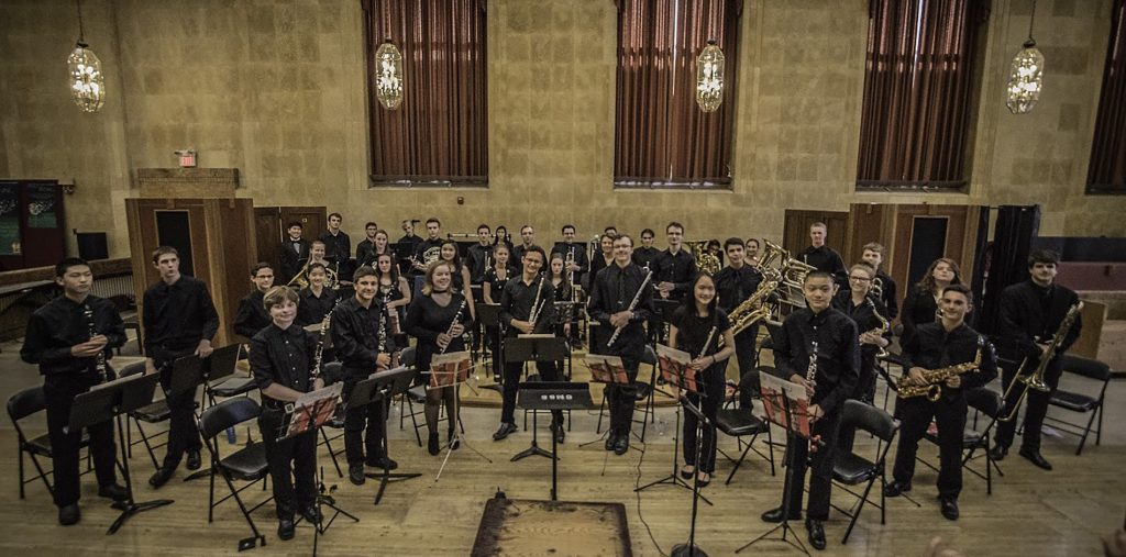 Youth Wind Ensemble students standing with their instruments after performing