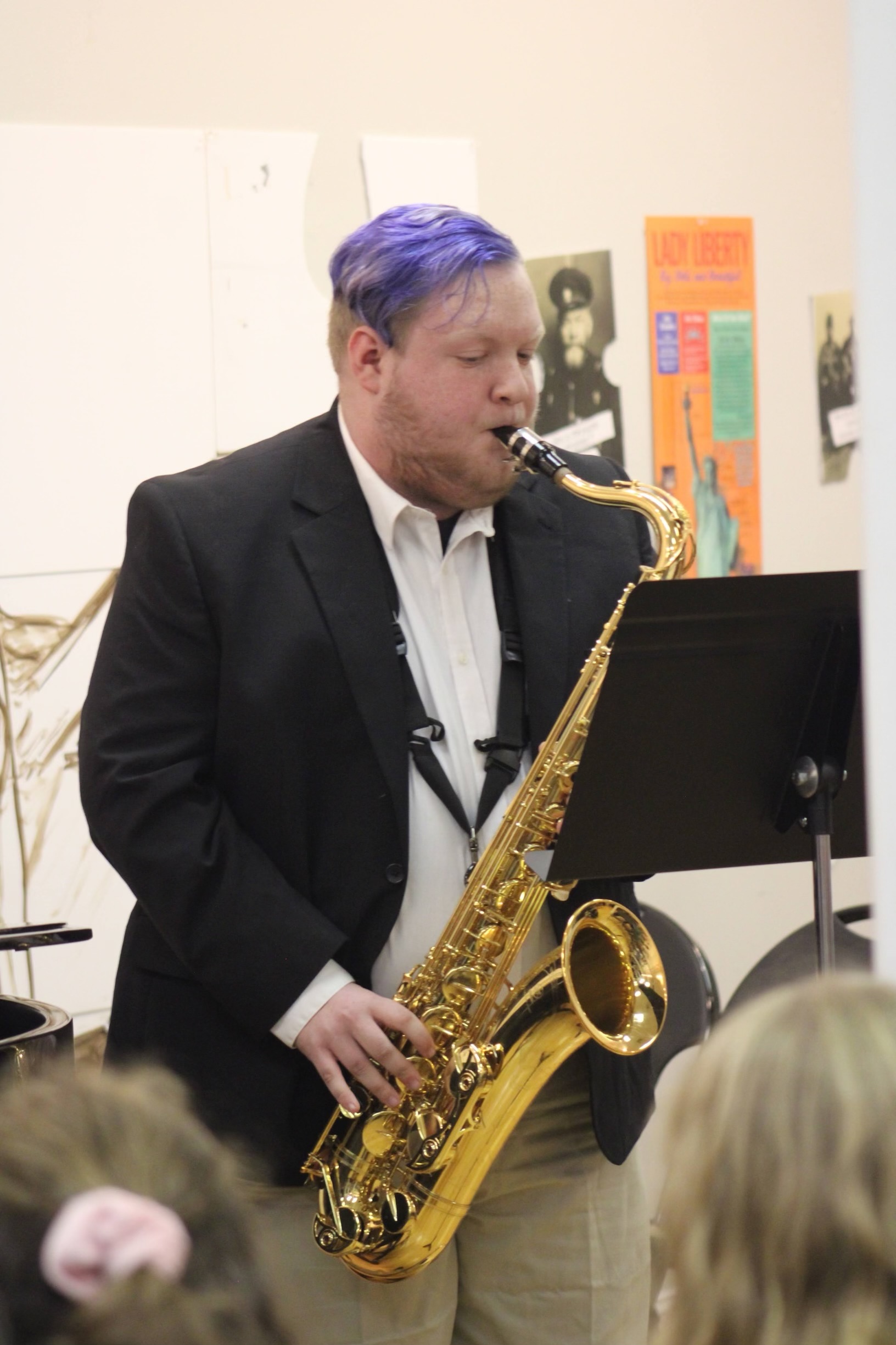 A young man with purple hair playing a saxophone