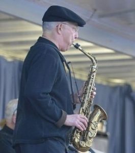 Ed Mari standing and playing saxophone in a concert