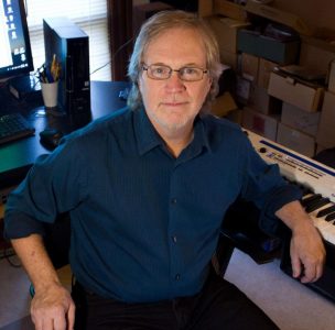 Steve Moser sitting at a keyboard turned around and smiling