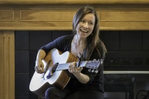 woman happily playing guitar