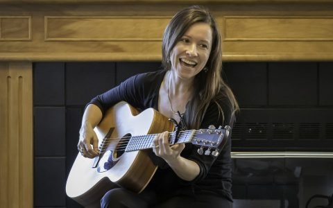 woman happily playing guitar