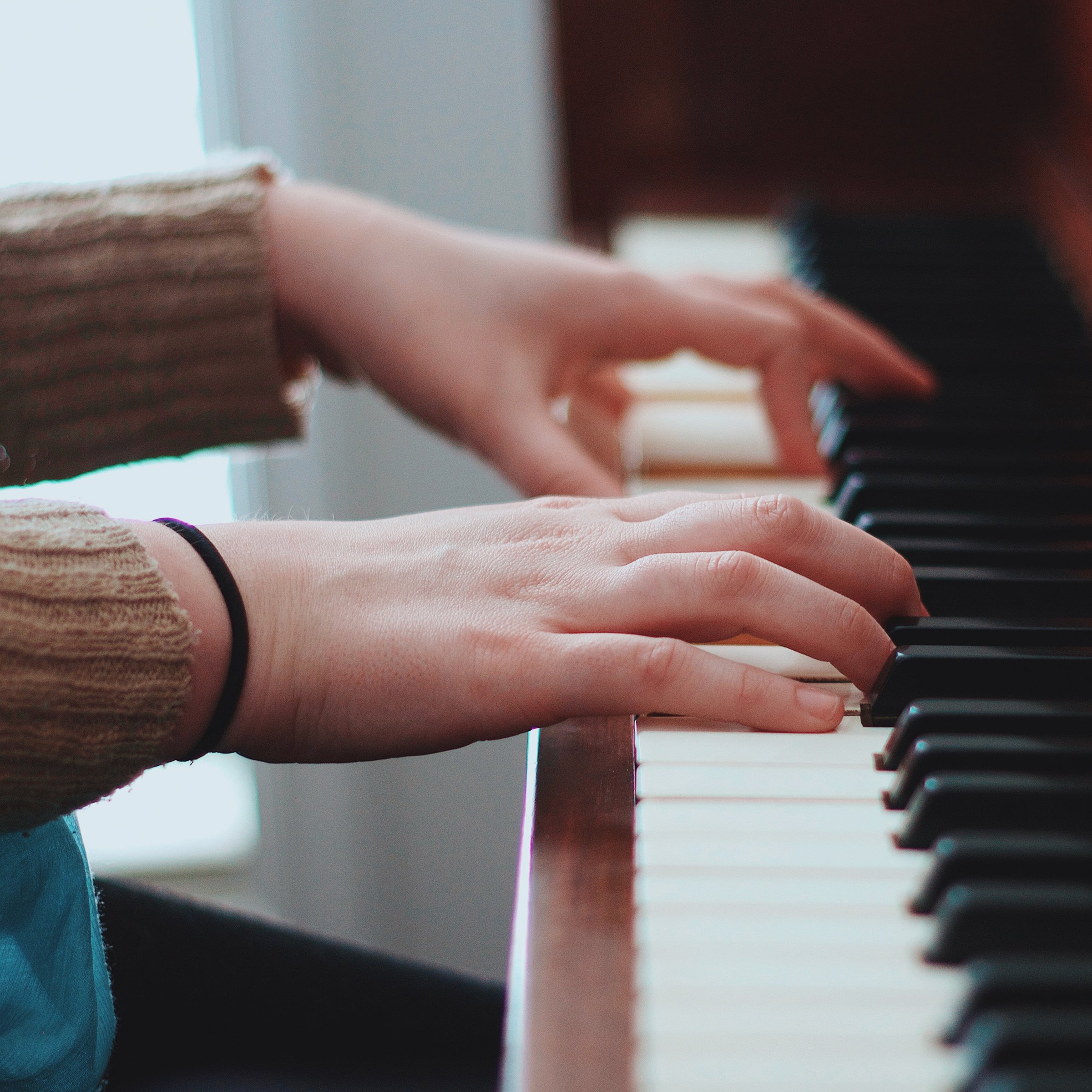person wearing brown sweater playing piano