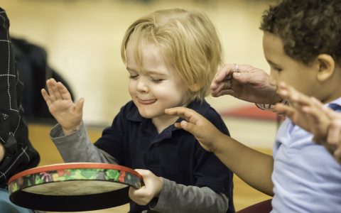 Close up of prelude student playing a small hand drum during music class