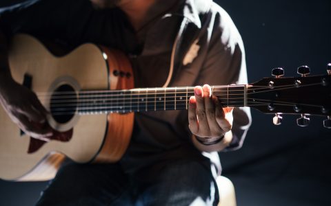 the torso of someone playing an acoustic guitar