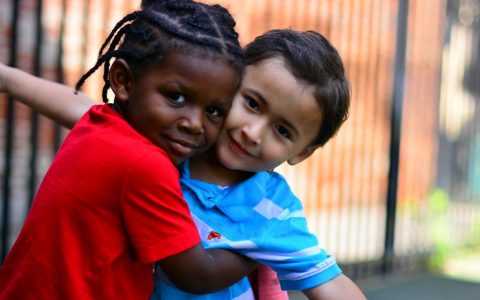 Two prelude students hugging each other outside and smiling