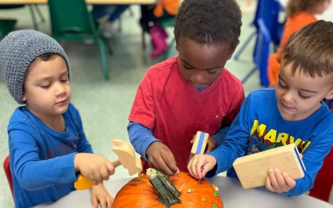 three children decorating a pumpkin