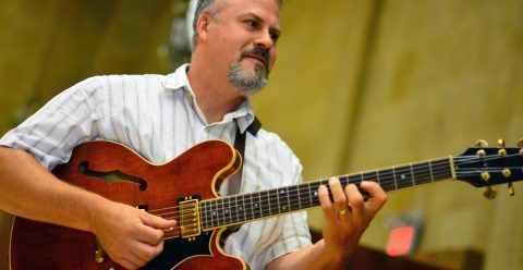 Scott Sasanecki playing the electric guitar in Robyn Newhouse Hall