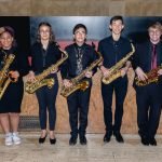 The saxophone section of YWES posing with their saxophones after a concert in Robyn Newhouse Hall