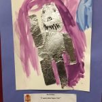 Prelude preschool art piece, a "Supergirl" robot made of tin foil with painting in the background and a blue paper border