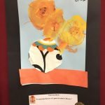 Prelude preschool art piece, blue paper with vase of flowers and a black border, made from construction paper and paint