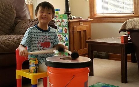 prelude student playing bucket drum in living room