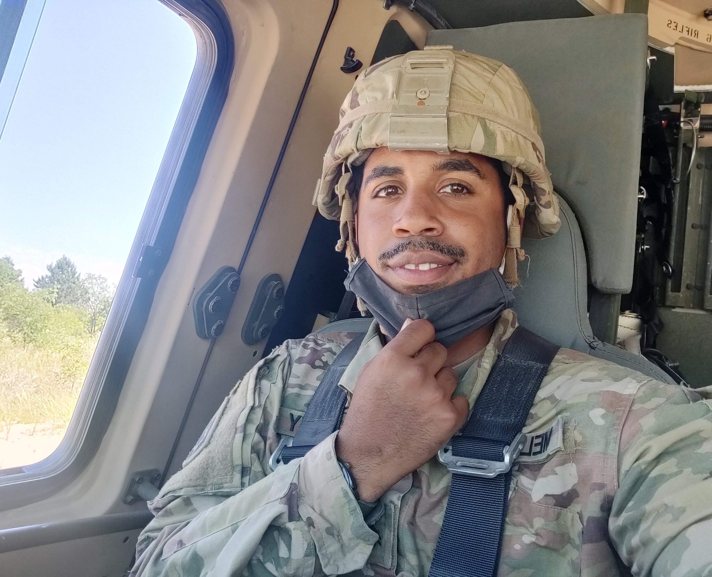 Tynayko Melendez in uniform for the Army National Guard, smiling in a vehicle on duty