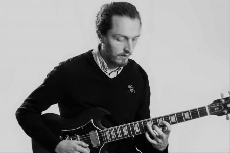 Chris playing electric guitar, looking calmly down at the instrument