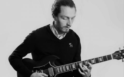 Chris playing electric guitar, looking calmly down at the instrument
