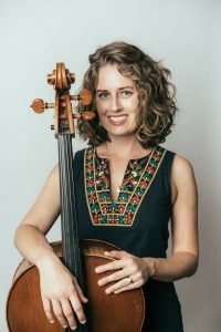 woman standing with her arm over a cello