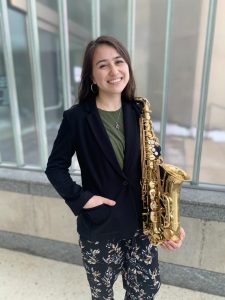 woman in mid-20s with straight brown hair holding saxophone
