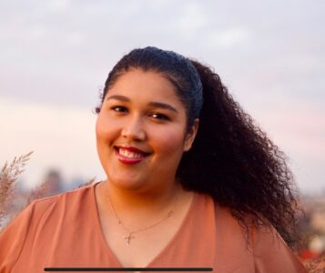A woman looking at the camera and smiling with sky in the background